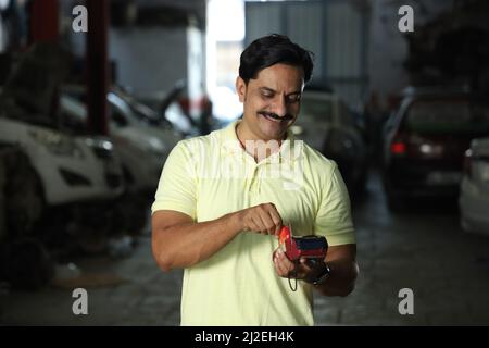 A photo of a happy Indian client in a motor shop using the credit or a debit card for digital payment Stock Photo