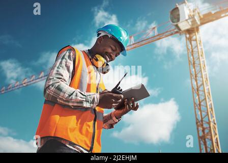 New age tech for new age construction. Shot of a young man using a digital tablet while working at a construction site. Stock Photo