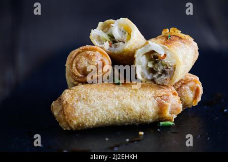 Fresh stack of egg rolls. Top eggroll is broken open to see the ingredients inside.Selective focus with blurred foreground and background. Stock Photo