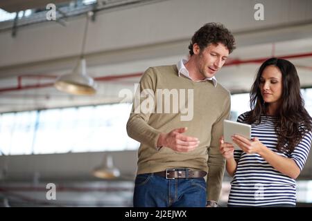 Going over the meeting points. Two creative professionals discussing something they are looking at on a digital tablet. Stock Photo