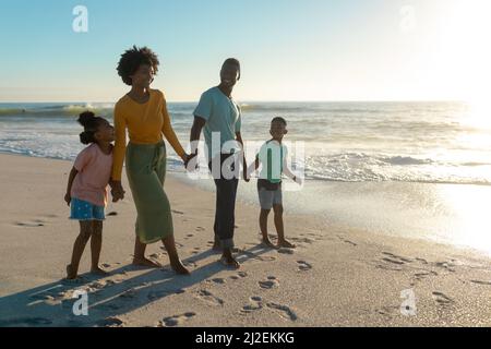 Full length of happy african american family enjoying summer holiday together at beach