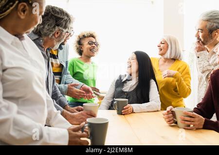 Happy multiracial people with different ages and ethnicities having fun drinking a cup of coffee at home Stock Photo