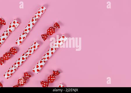 Red and white candy with wrapping with hearts on pink background Stock Photo