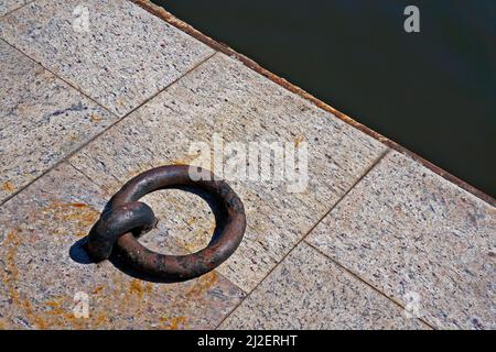 Old iron mooring ring on a stone dock Stock Photo