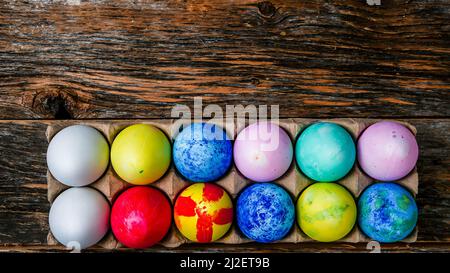 Painted and colored Easter eggs on rustic wooden table inside paper container with copy space above Stock Photo