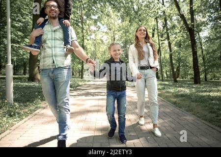 family with children walking along the path in the city Park Stock Photo