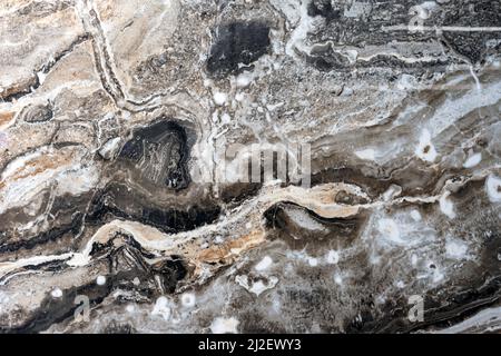Texture of natural gray-black quartz stone with beige mineral inclusions. Stock Photo