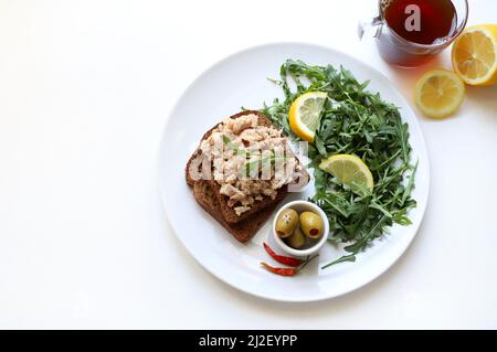 Slices of wholemeal bread with tuna, lemon and vegetables isolated on white background. Tuna appetizer. Directly above. Stock Photo