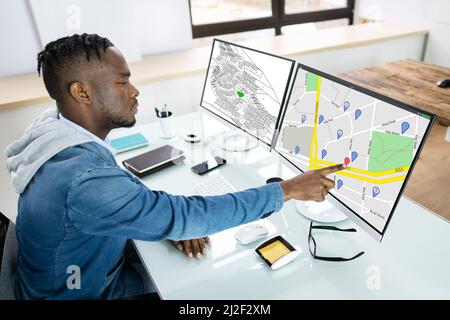 Businessperson Analyzing Cadastre Map On Computer In The Office Stock Photo