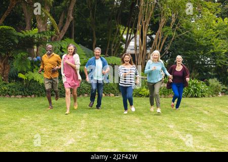 Carefree multiracial senior male and female friends running in backyard Stock Photo