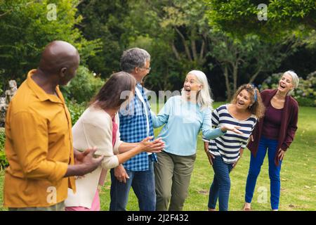 Happy multiracial senior male and female friends having fun in backyard Stock Photo