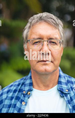 Portrait of confident caucasian senior man with eyeglasses in backyard on weekend Stock Photo