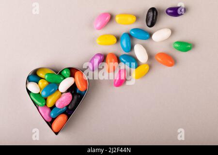 Overhead view of heart shape container with multi colored candies on white background Stock Photo
