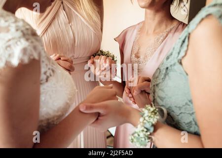 Morning of bride. Gorgeous bride with best bridesmaids are holding hands in hotel room. Wedding morning details. High quality photo. Stock Photo