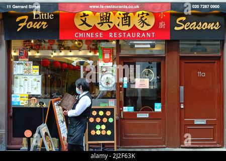 Exterior of a colourful chinese restaurant with a waitress looking for  customers, Gerrard Street Chinatown Central London England UK Stock Photo