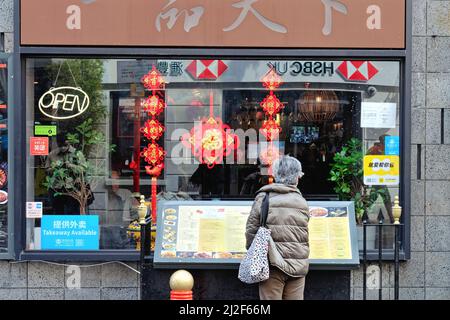 Rear view of a grey haired mature lady looking at a menu board outside of a chinese restaurant on Gerrard Street Chinatown Central London England UK Stock Photo