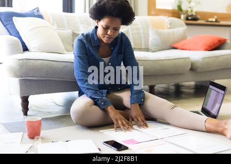 Mid adult african american female freelancer analyzing documents at home Stock Photo