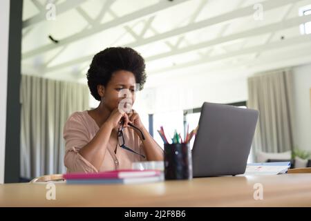 Concentrated mid adult african american female freelancer using laptop at desk Stock Photo