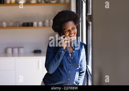 Mid adult african american female freelancer using talking on mobile phone at home Stock Photo