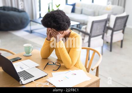 Tired mid adult african american female freelancer working on laptop at desk Stock Photo