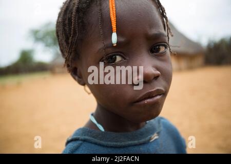 Girl with traditional hair braids and a sad expression in Omusati Region, Namibia, southwest Africa. Stock Photo