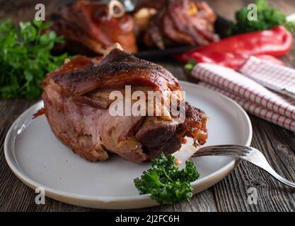 Ham hock or pork knuckle fresh and homemade oven baked. Served on rustic and wooden table background Stock Photo