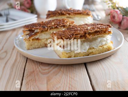 Sliced cakes on a plate. Delicious sheet cake filled with whipped cream and caramelized almond topping Stock Photo