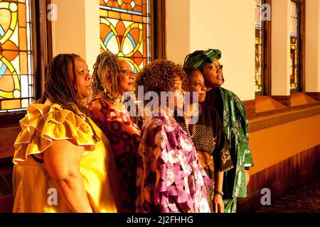 Location shot of colorfully dressed older African women in a church looking into the morning sun Stock Photo