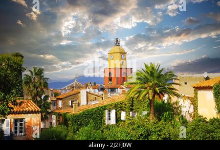 Scenic view on mediterranean village with church tower, palm trees, dramatic sky with autumn storm clouds - St. Tropez, France Stock Photo