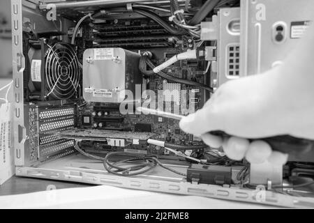 a screwdriver is held in an unscrewed PC Stock Photo