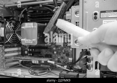 a hammer is held in front of an unscrewed PC Stock Photo