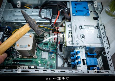 a hammer is held in front of an unscrewed PC Stock Photo