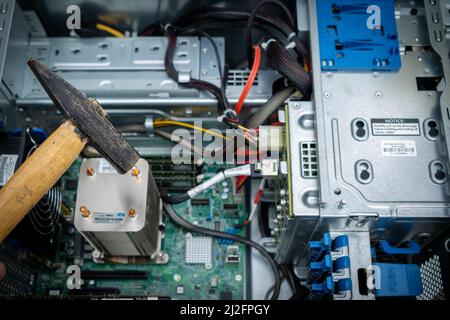 a hammer is held in front of an unscrewed PC Stock Photo