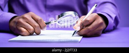 Auditor Using Magnifying Glass For Audit And Fraud Investigation Stock Photo