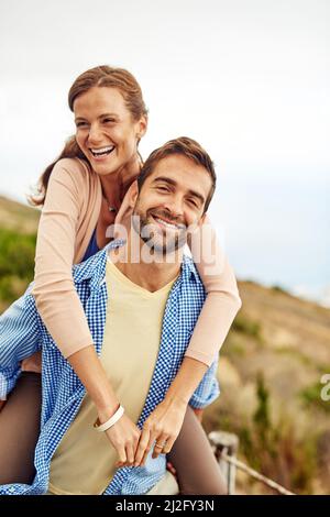 Were having such a good time together. Cropped shot of a man piggybacking his girlfriend while spending the day outdoors. Stock Photo