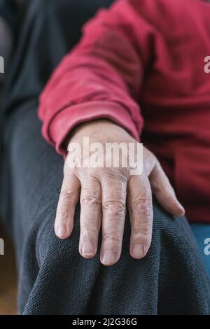 elderly person's hand resting on armchair Stock Photo