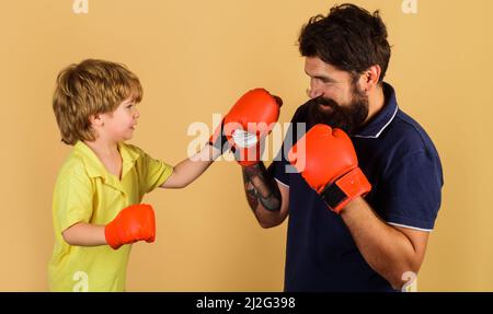 Father and son during boxing training. Child boy boxer in gloves practicing punches with coach. Stock Photo