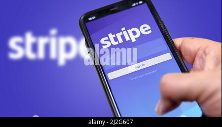 San Francisco, CA, USA, March 15, 2021: Stripe's application login page on the screen of a hand held smartphone. Background with blurry Stripe logo. S Stock Photo