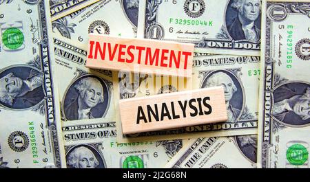 Investment analysis symbol. Wooden blocks with concept words Investment analysis on beautiful background from dollar bills. Business investment analys Stock Photo