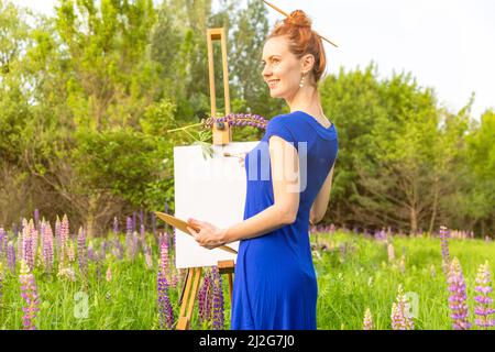 Artist woman with easel on nature background Stock Photo