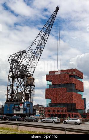 The modern exterior of the Museum Aan de Stroom and a crane in Antwerp, Belgium Stock Photo