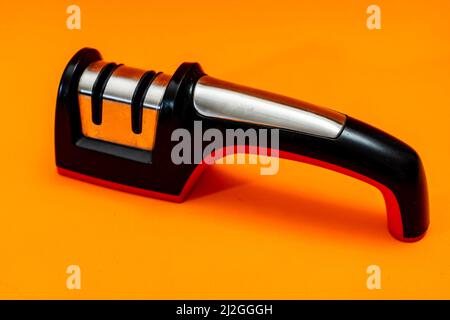 Knife sharpener isolated on an orange background. Stock Photo