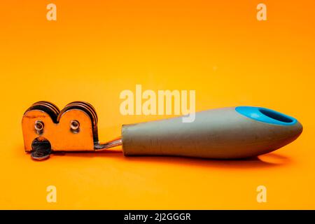 Knife sharpener isolated on an orange background. Inexpensive non-professional kitchen utensil. Stock Photo