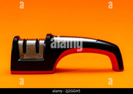 Knife sharpener isolated on an orange background. Stock Photo