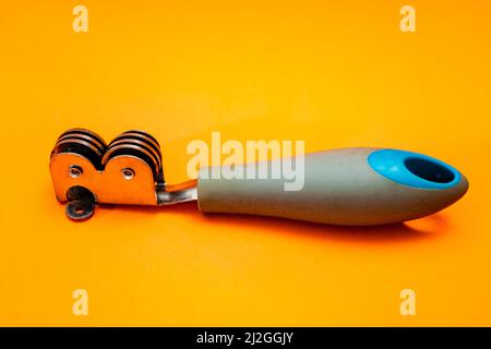 Knife sharpener isolated on an orange background. Inexpensive non-professional kitchen utensil. Stock Photo