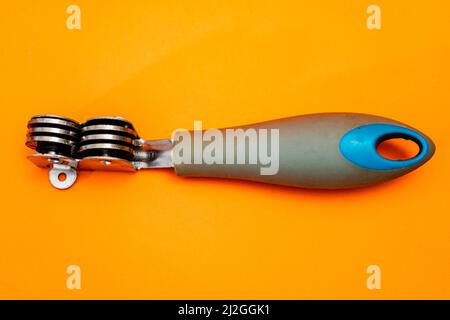 Knife sharpener isolated on an orange background. Inexpensive non-professional kitchen utensil. Stock Photo