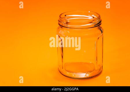 Empty hexagonal glass flask isolated on orange bottom. Stock Photo