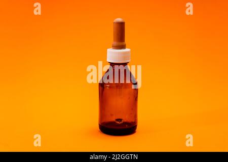 Small bottle with amber glass dropper insulated on orange background. copy space. Stock Photo