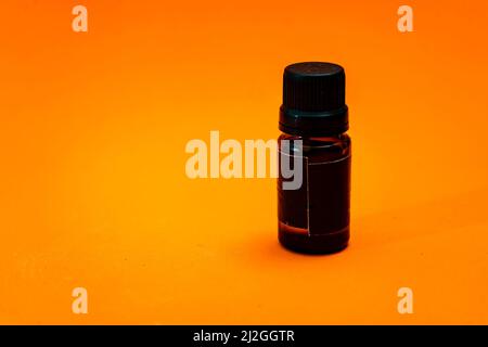 Small amber glass dropper bottle insulated on orange background. copy space. Stock Photo