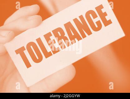 Tolerance words on a card in businessman hand. Social concept against discrimination at workplace. Stock Photo